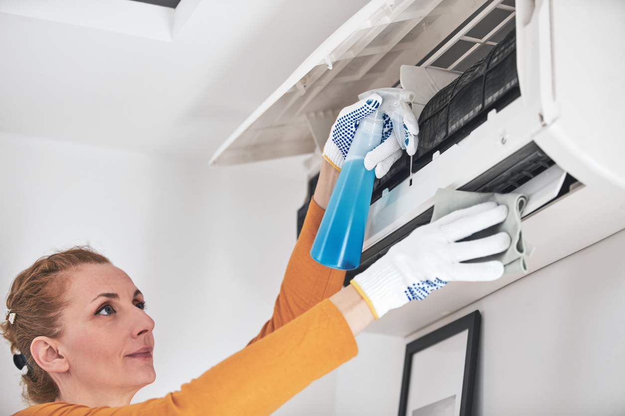 Woman cleaning aircon filters indoor unit at home.